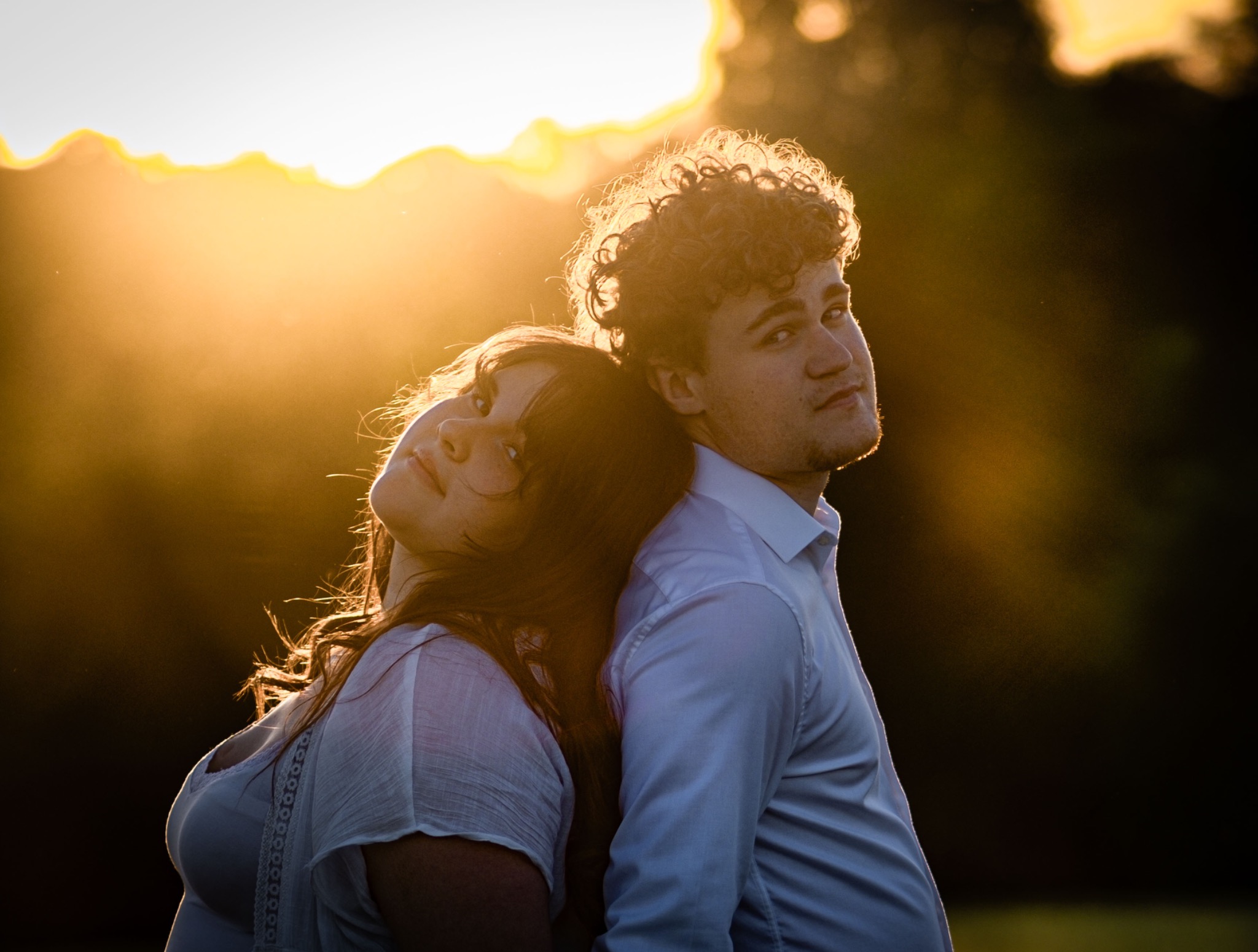 Couple photographié à contre-jour dans un champ au coucher du soleil