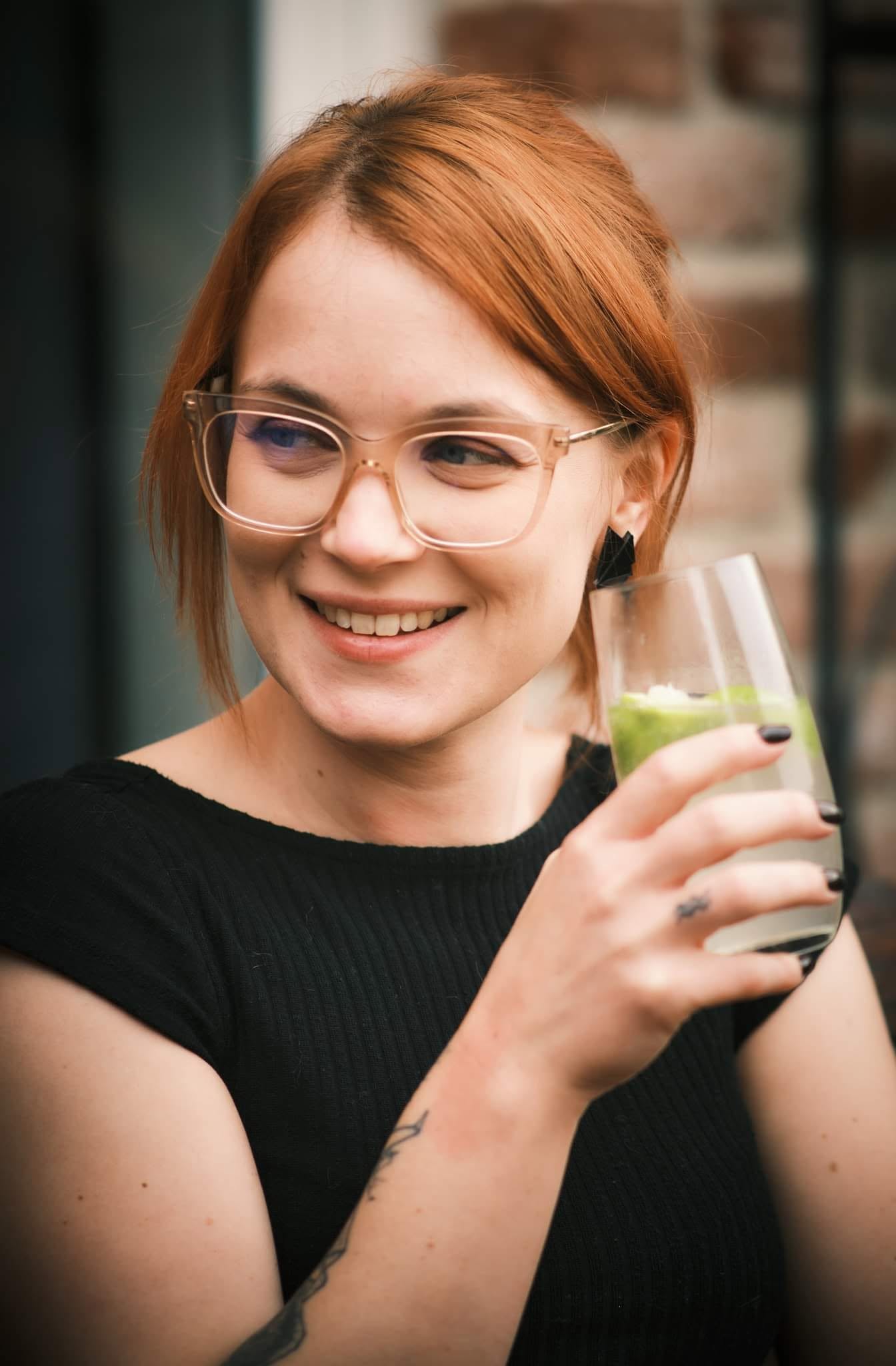 Femme rousse souriant avec un verre à la main